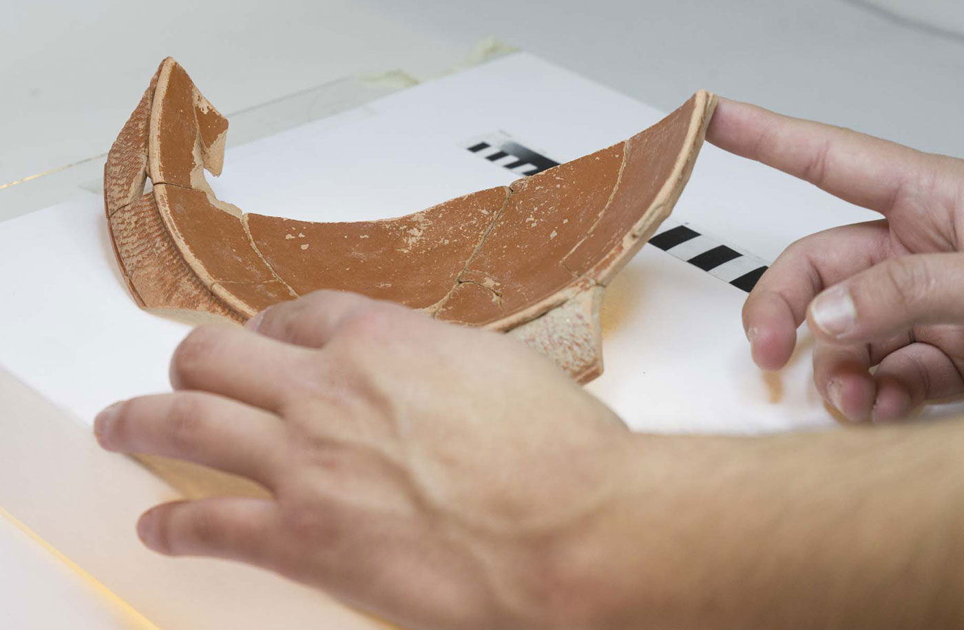 As mans dunha persoa que investiga sosteñen un anaco de cerámica antiga