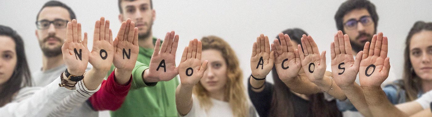 Varias rapazas e rapaces miran á cámara e teñen pintadas nas palmas das mans a frase "Non ao acoso"