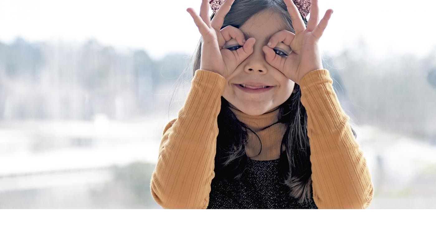 Nena coas mans colocadas en forma de lentes sobre os ollos