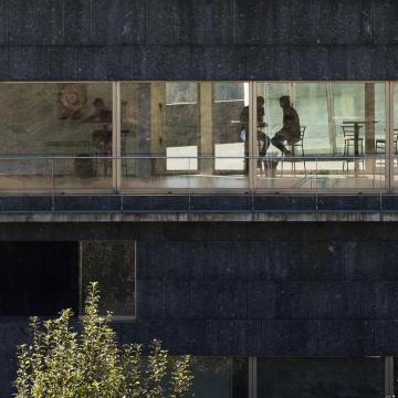 Dúas persoas charlan sentadas no interior dun edificio