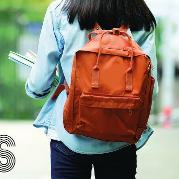 Estudante de costas cunha mochila marrón e libros na man
