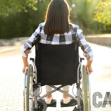 Rapaza de costas nunha cadeira de rodas para difundir o Día da Persoas con Discapacidade
