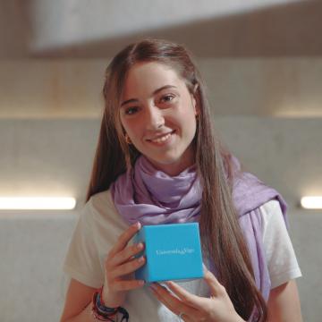 Estudante de grao da Universidade de Vigo cunha caixa azul co logotipo da UVigo nas mans